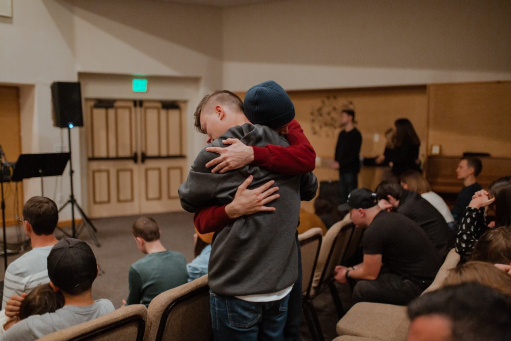 Two men hugging each other in class demonstrating empathy of John R Miles blog