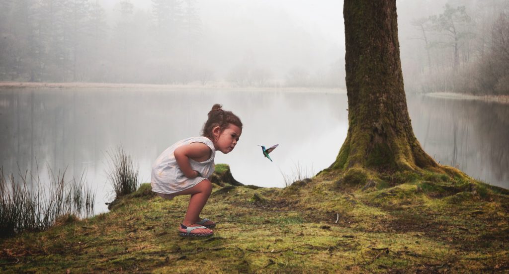 Young girl demonstrating curiosity as she observes a hummingbird