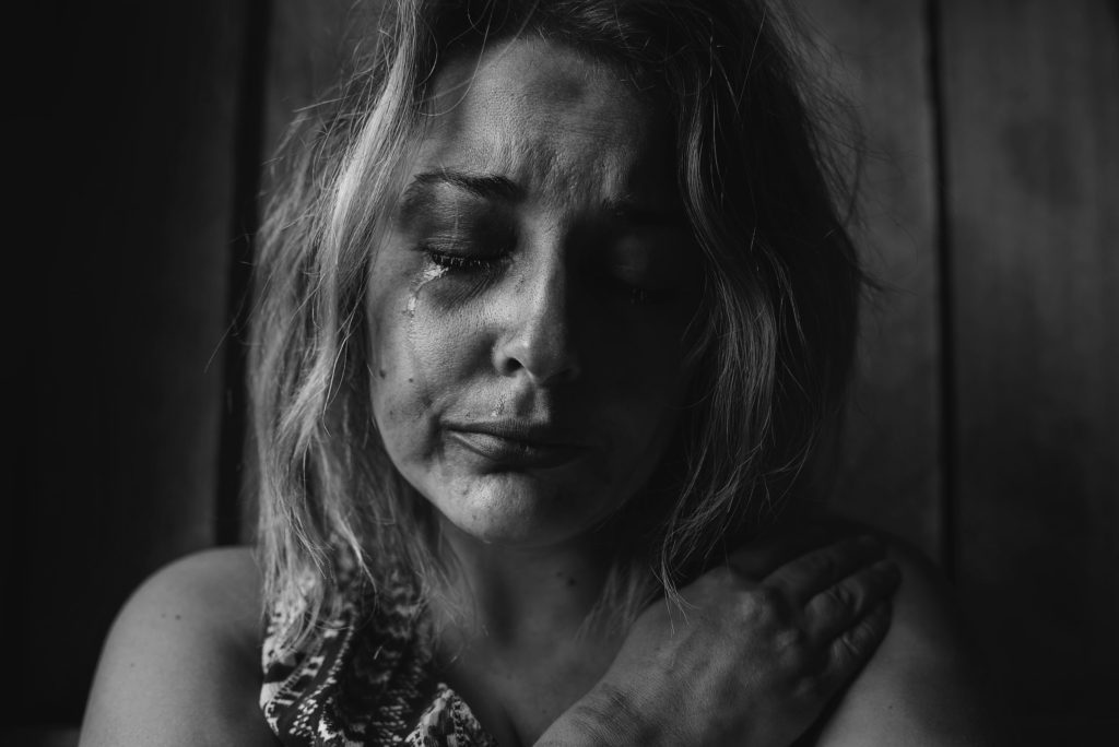 Black and white picture of a woman crying who is suffering from chronic loneliness
