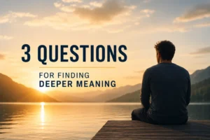 A contemplative figure sits on a wooden dock overlooking a calm mountain lake at sunrise, symbolizing reflection, presence, and the journey toward finding deeper meaning in life. The image includes the title “3 Questions for Finding Deeper Meaning” in bold, minimalist typography against a serene natural landscape.
